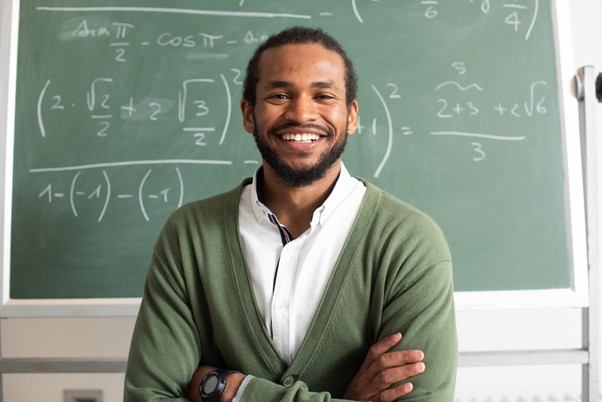 Teacher smiling warmly in a classroom setting.